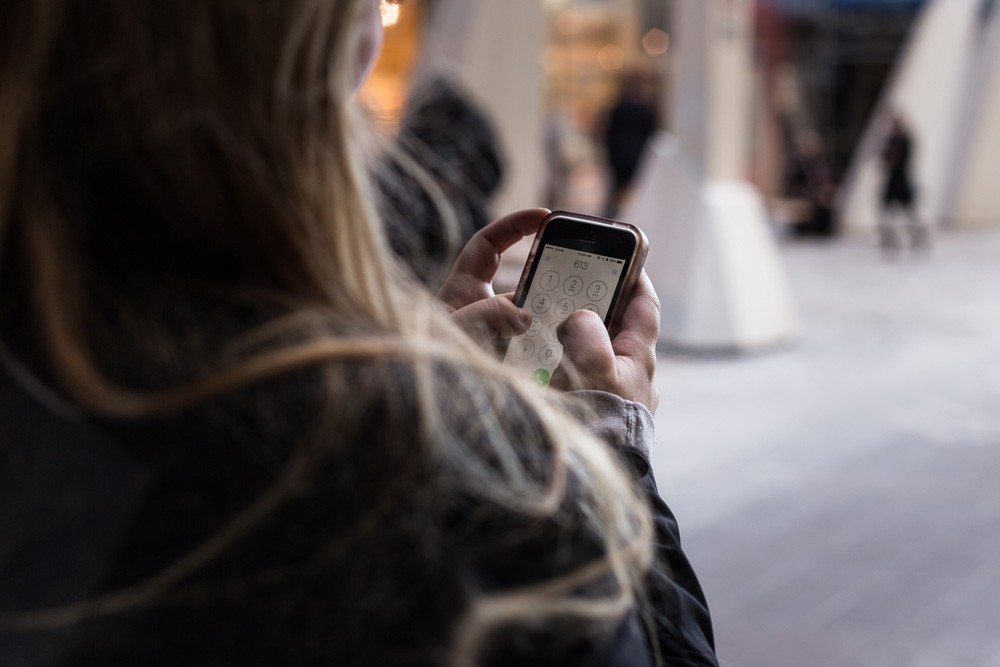 chica morena tecleando un número de teléfono en el móvil